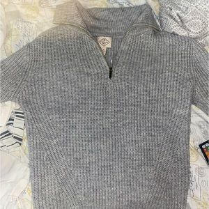 A grey sweater with a turtle neck zip up. Made softly knitted fabric.